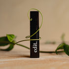 Black cylindrical product with 'edit.' branding on a wooden surface with green leaves.